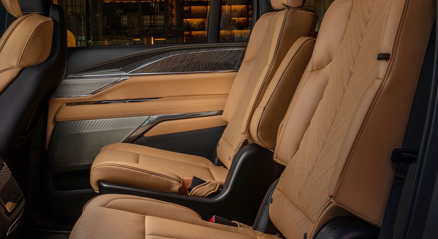 Luxurious Cadillac Escalade IQ car interior with tan leather seats and sleek wood-paneled door accents. The seats are plush, emphasizing comfort and sophistication.